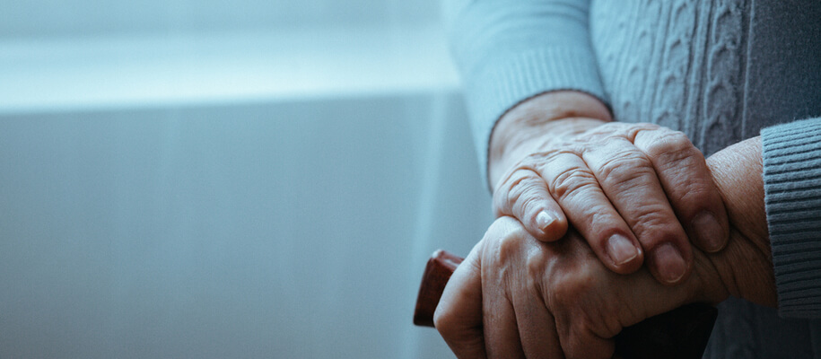 a senior's hands holding a cane.