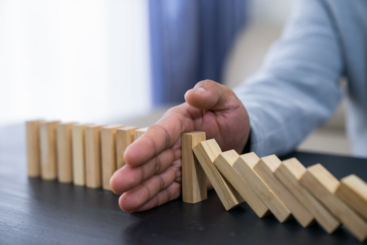 A man stopping bricks from falling, representing crisis management.