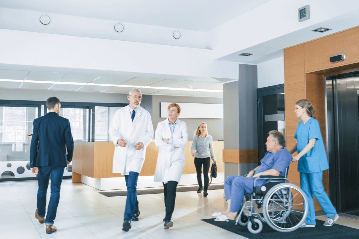 A nurse wheels a patient out of a hospital to a post-acute care facility.